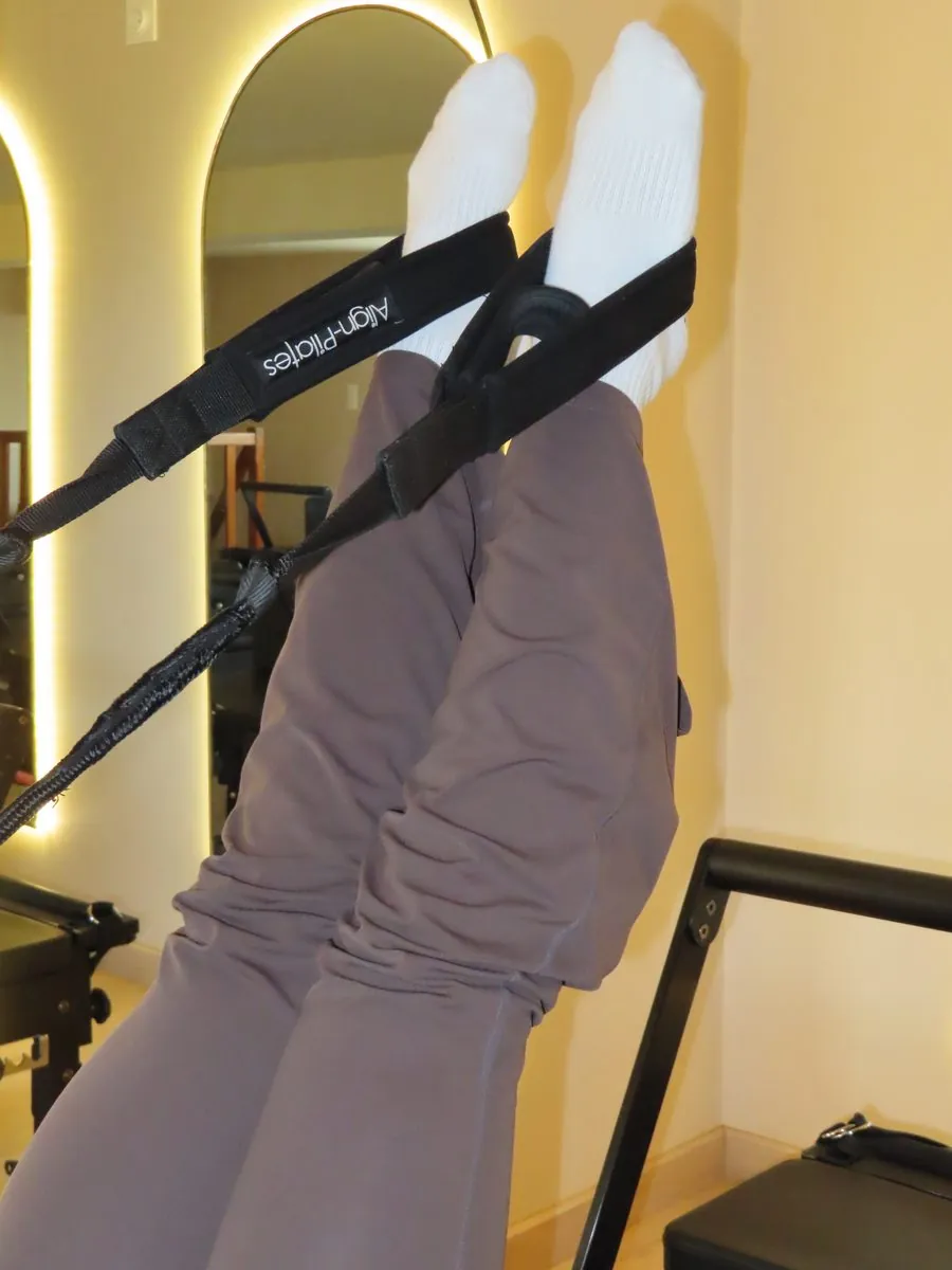 Jambes tendues vers le ciel dans les sangles du Reformer